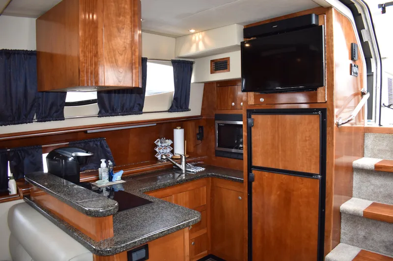 Slide: The Image of Die Küche der Cruisers Yachts 415 Express Motoryacht von 2006 verfügt über Holzschränke, eine Arbeitsplatte und einen Fernseher. - 9