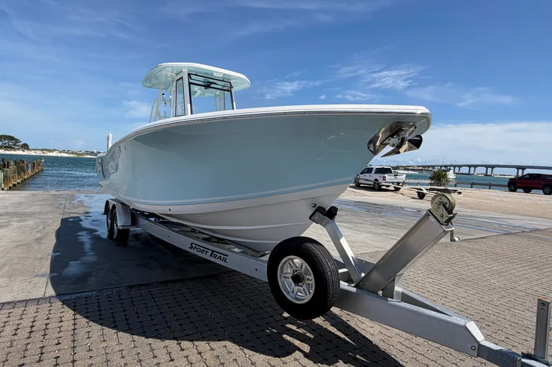 Slide: The Image of 2023 Tidewater 292 CC Adventure boat on trailer by waterfront, clear sky background. - 2
