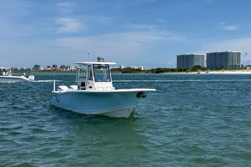 Slide: The Image of 2023 Tidewater 292 CC Adventure boat cruising near coastal buildings. - 27