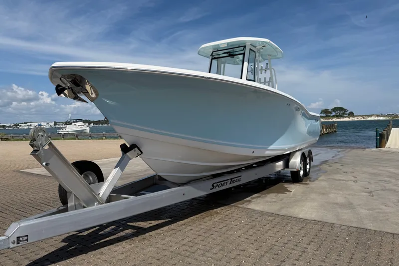 Slide: The Image of 2023 Tidewater 292 CC Adventure boat on trailer by waterfront under blue sky. - 1