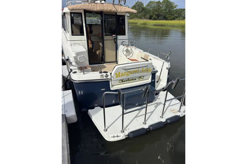 Slide: The Image of 2016 Cutwater C-28 boat docked, rear view with open cabin and water backdrop. - 9