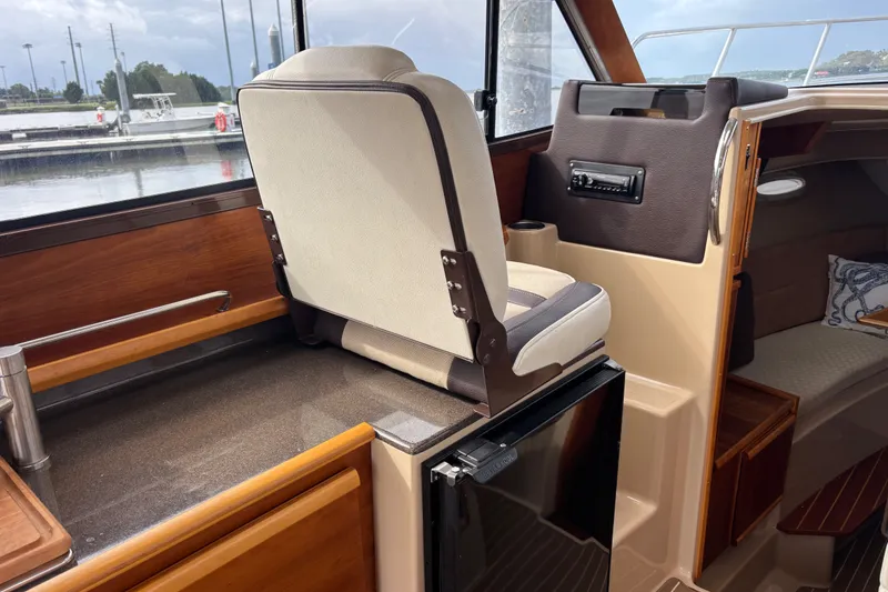 Slide: The Image of Interior of a 2016 Cutwater C-28 boat featuring a companion seat and compact kitchenette. - 29