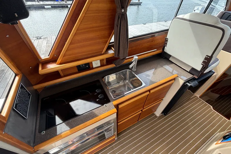 Slide: The Image of 2016 Cutwater C-28 Galley with stainless steel sink, stovetop, convection microwave oven and wooden cabinetry. - 31