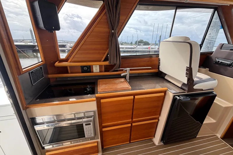 Slide: The Image of 2016 Cutwater C-28 Galley with stainless steel sink, stovetop, convection microwave oven and wooden cabinetry. - 30