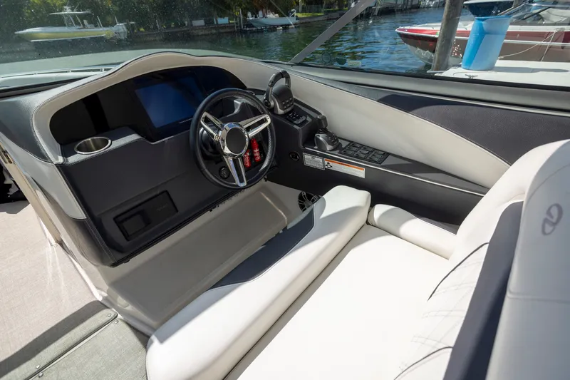 Slide: The Image of 2023 Regal 3300 Bowrider cockpit with modern steering and controls, docked by the water. - 22
