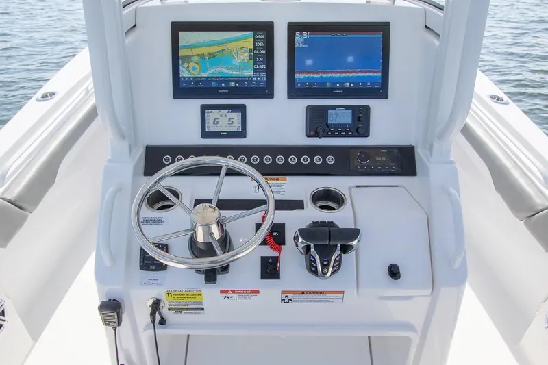 Slide: The Image of Manufacturer Provided Image: 2026 Regulator 25 boat dashboard with navigation screens and steering wheel on water. - 5