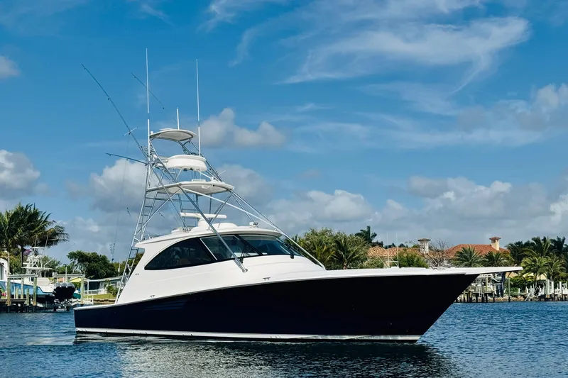 Slide: The Image of 2017 Viking 52 Sport Tower yacht on calm water under blue sky. - 2