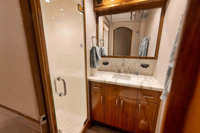 Slide: The Image of Luxurious bathroom interior of 2015 Hatteras GT70 yacht with wooden cabinetry and glass shower. - 54