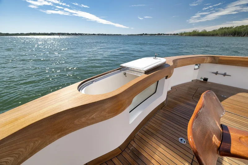 Slide: The Image of Luxurious 2015 Hatteras GT70 yacht deck with wooden finish, overlooking serene waters. - 16