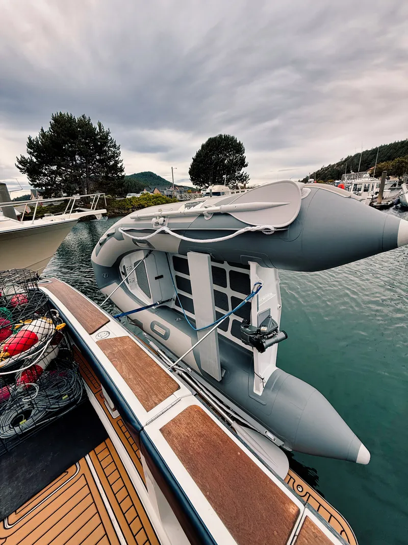 Slide: The Image of An inflatable boat is secured to the side of a larger boat docked in a calm harbor. - 16