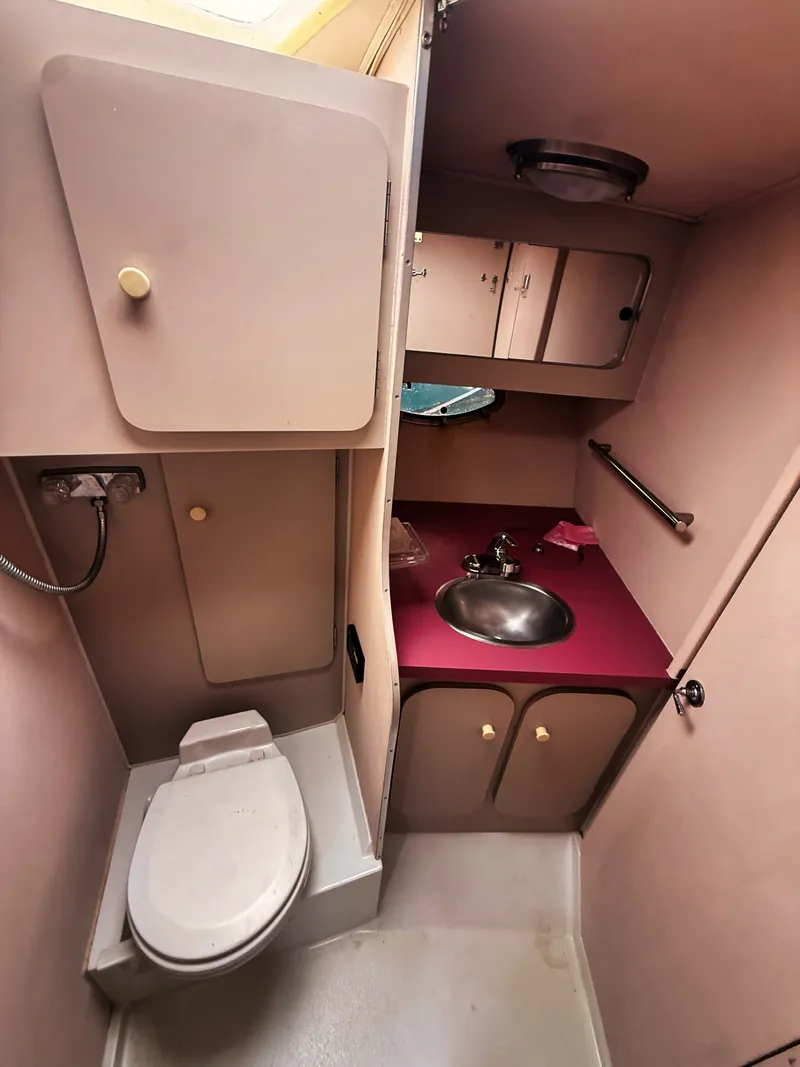 Slide: The Image of The image shows a boat bathroom with a toilet, sink, and storage space. - 14