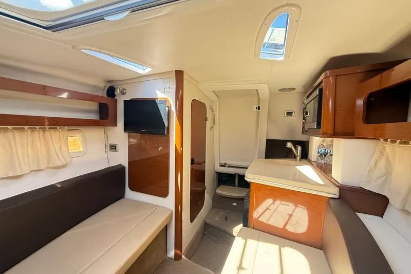 Slide: The Image of Interior of 2014 Sea Ray 265 Sedan Bridge with seating, kitchenette, and TV. - 15