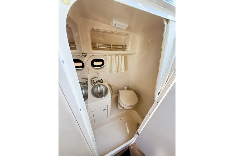 Slide: The Image of Compact bathroom in 2014 Sea Ray 265 Sedan Bridge boat, featuring sink and toilet. - 16
