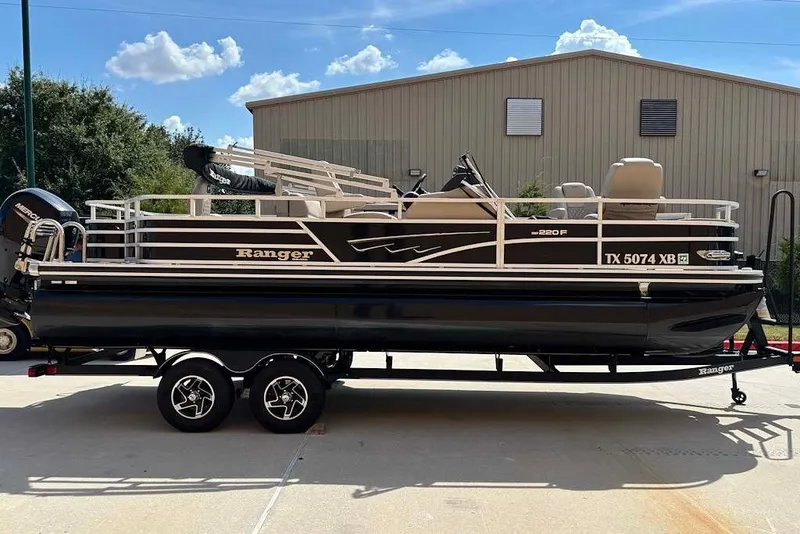The Image of 2024 Ranger Reata 220F pontoon boat on trailer, parked outdoors. - 0