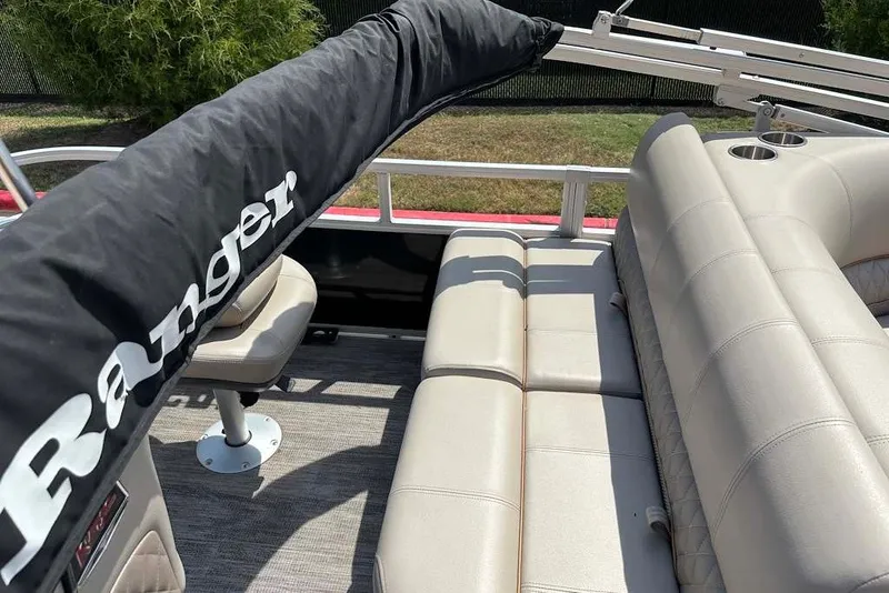 Slide: The Image of 2024 Ranger Reata 220F boat interior with beige seating and protective cover. - 8
