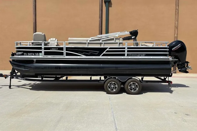 Slide: The Image of 2024 Ranger Reata 220F pontoon boat on trailer, side view, black and silver design. - 1