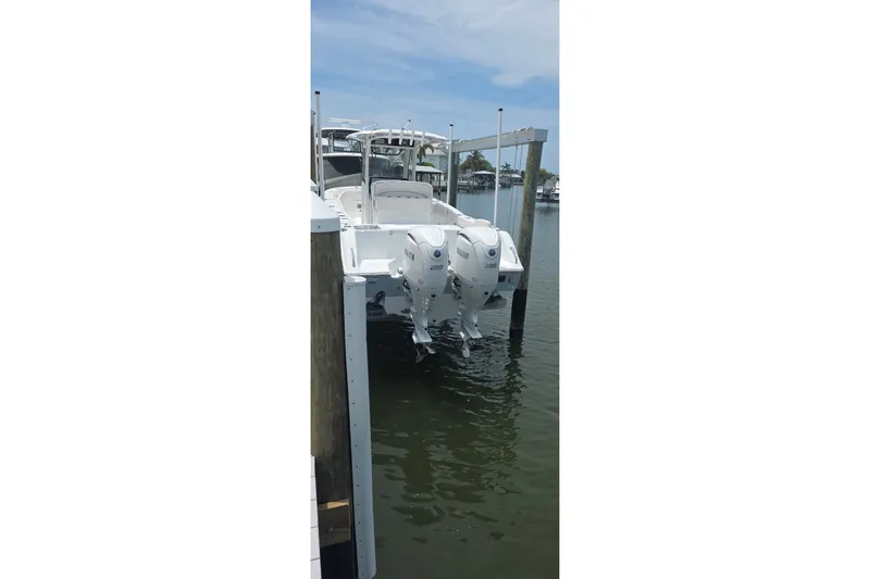Slide: The Image of 2025 Sea Hunt Gamefish 27CB boat docked with dual outboard engines. - 13