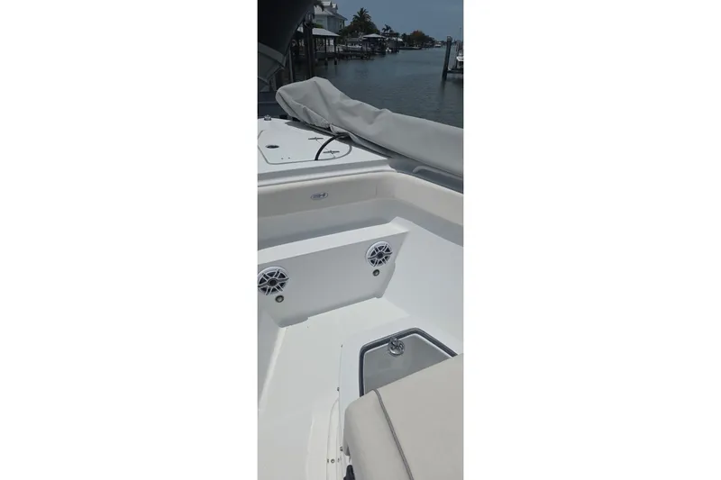 Slide: The Image of 2025 Sea Hunt Gamefish 27CB boat interior with speakers and seating, docked by the water. - 18