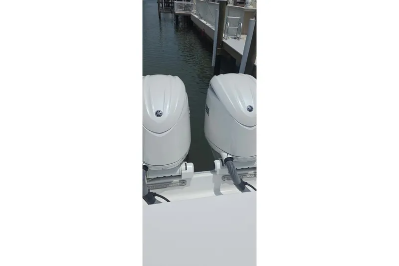 Slide: The Image of Twin outboard engines on a 2025 Sea Hunt Gamefish 27CB boat docked by the water. - 15