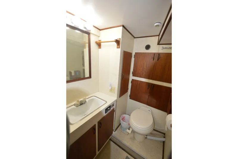 Slide: The Image of Bathroom interior of 1973 Hatteras 36 Sport Fisherman with sink, mirror, and wooden cabinets. - 34