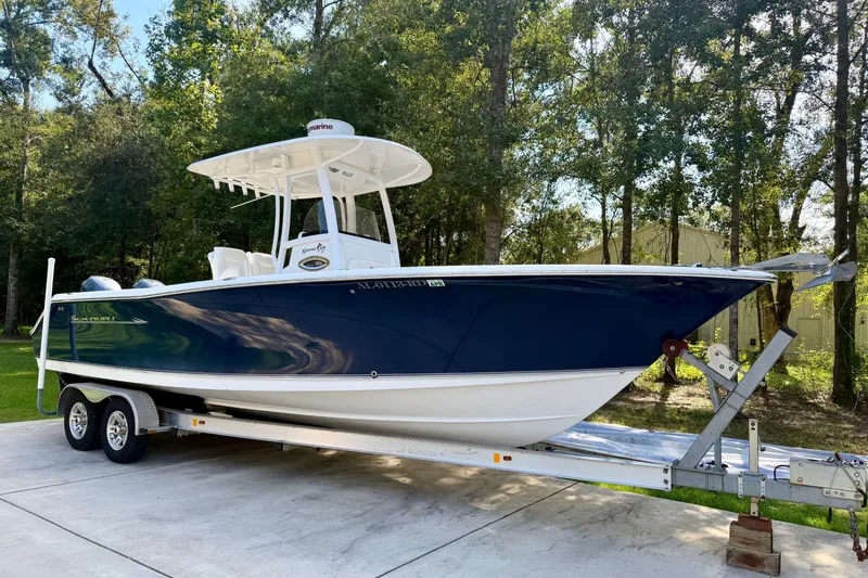 The Image of 2013 Sea Hunt Gamefish 27 boat on trailer, parked outdoors with trees in background. - 1