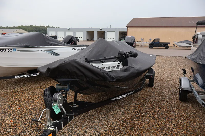 Slide: The Image of 2021 Lowe Stinger 195C boat covered, parked on gravel lot with other boats. - 43