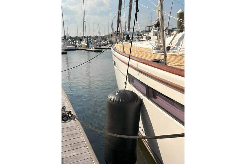 Slide: The Image of 2012 Jeanneau 57 yacht docked with fender, marina background. - 14