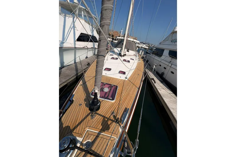 Slide: The Image of 2012 Jeanneau 57 sailboat docked, showcasing sleek wooden deck and rigging. - 13