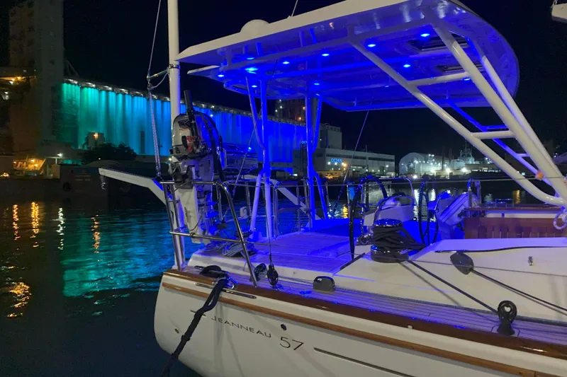 Slide: The Image of Jeanneau 57 sailboat, 2012 model, docked at night with blue lights reflecting on water. - 23
