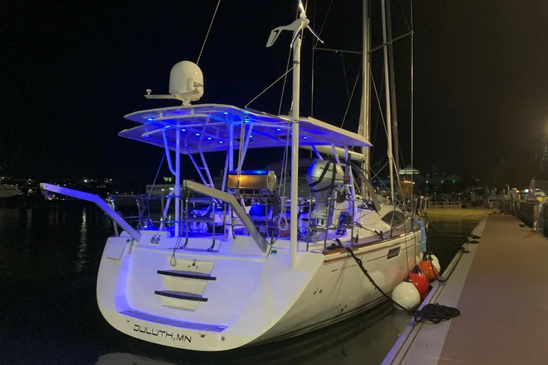 Slide: The Image of 2012 Jeanneau 57 yacht docked at night with blue deck lights. - 24