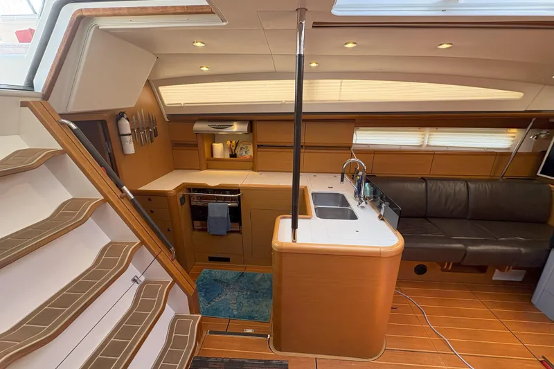 Slide: The Image of Interior of 2012 Jeanneau 57 yacht featuring kitchen, seating, and wooden flooring. - 48