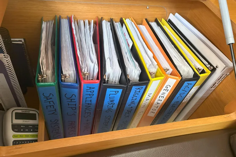 Slide: The Image of Binders with labels for safety, ship's papers, appliances, plumbing, and more on a Jeanneau 57 yacht. - 36