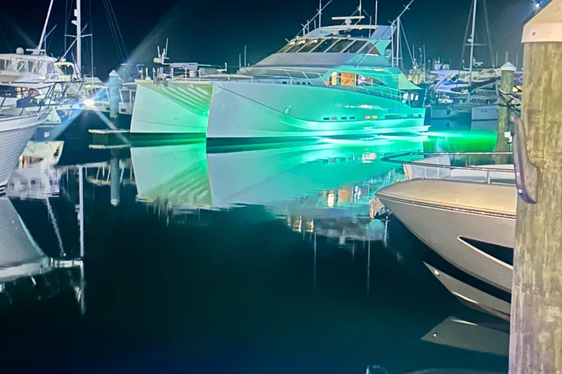 Slide: The Image of A lit-up sportfish catamaran docked at night, surrounded by other boats. - 1