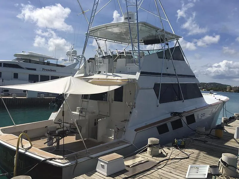 Slide: The Image of Eine Hatteras 65 Convertible von 1988 liegt an einem sonnigen Dock. Sie hat ein geräumiges Deck und eine markante Flybridge. - 17