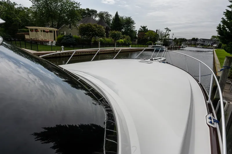 Slide: The Image of 2022 Viking 48 Convertible yacht docked in a serene canal setting. - 30