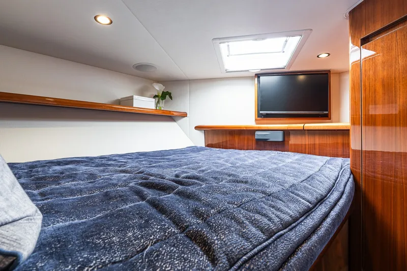 Slide: The Image of Luxurious cabin interior of 2022 Viking 48 Convertible yacht with cozy bedding and TV. - 49