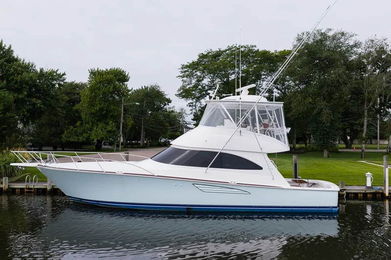 Slide: The Image of 2022 Viking 48 Convertible yacht docked by lush greenery. - 1