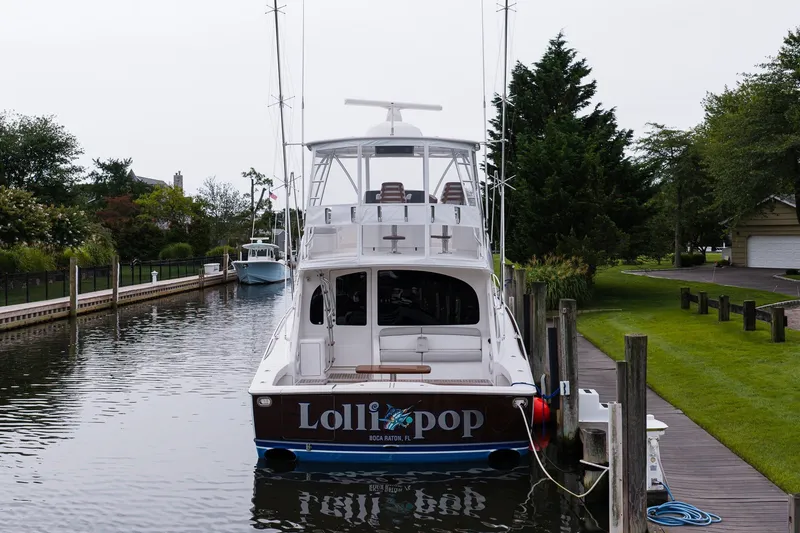 Slide: The Image of 2022 Viking 48 Convertible yacht docked in a serene canal setting. - 3