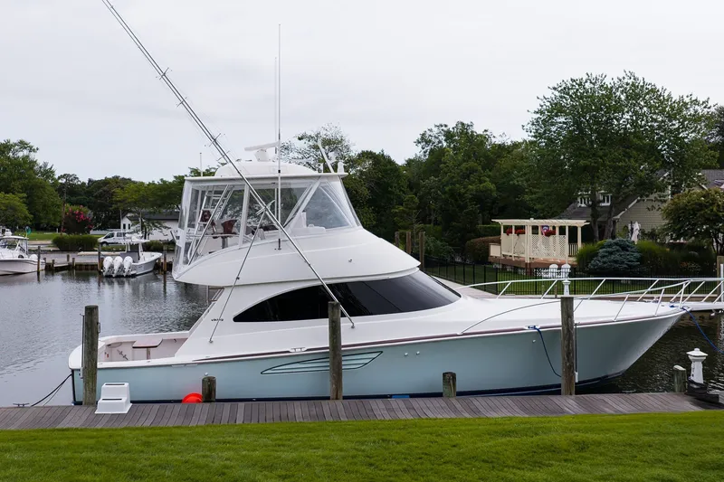 Slide: The Image of 2022 Viking 48 Convertible yacht docked by a serene waterfront. - 5