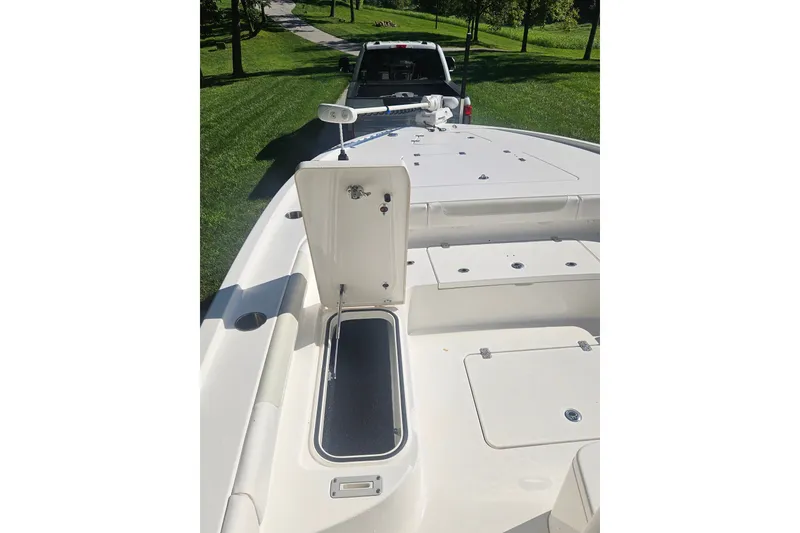Slide: The Image of 2021 Caymas 28 HB boat deck with open storage compartment, parked on grass. - 10