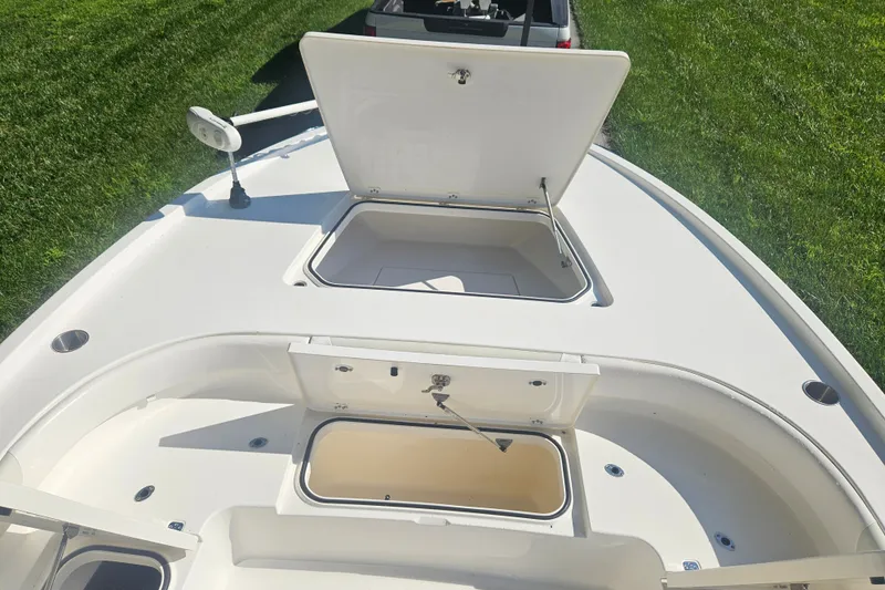 Slide: The Image of 2021 Caymas 28 HB boat deck with open storage compartments, on grassy background. - 12