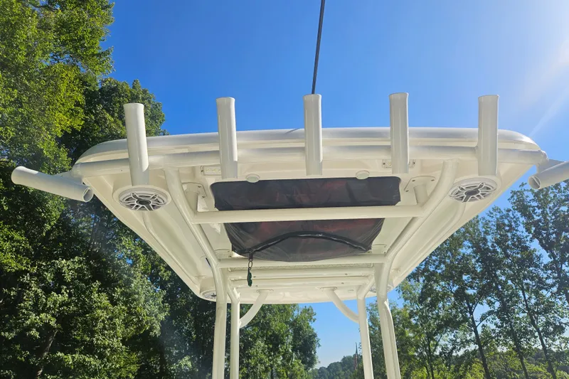 Slide: The Image of T-top of 2021 Caymas 28 HB boat with rod holders and speakers, under clear blue sky. - 6