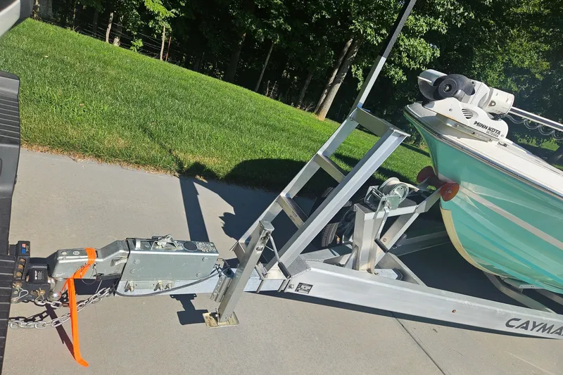 Slide: The Image of 2021 Caymas 28 HB boat on trailer, parked on driveway with lush green background. - 33