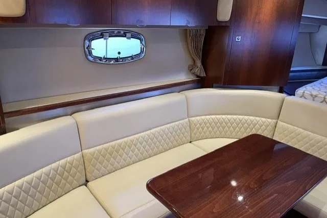 Slide: The Image of Interior of 2015 Chaparral 310 Signature yacht with beige seating and wooden table. - 19