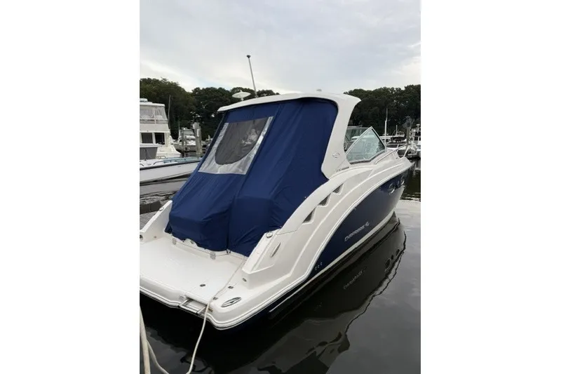 Slide: The Image of 2015 Chaparral 310 Signature boat docked with blue cover, rear view. - 15