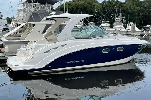 Slide: The Image of 2015 Chaparral 310 Signature boat docked in a marina, featuring sleek design and blue hull. - 3