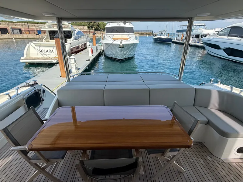 Slide: The Image of The 2022 Absolute 62 Fly is docked. It features a sleek aft deck with a table and chairs. - 10