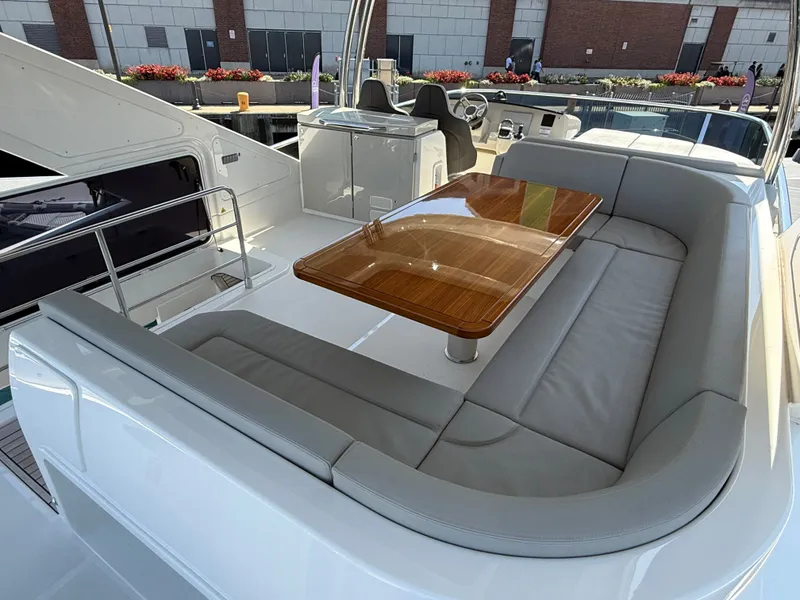 Slide: The Image of The image shows the deck of a 2022 Absolute 62 Fly with a sleek wooden table and gray seating cushions. - 11