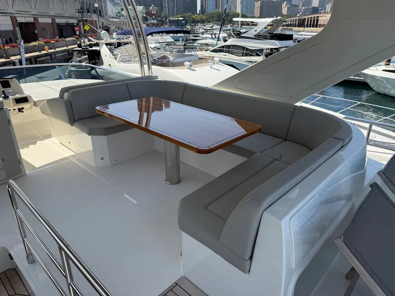 Slide: The Image of The 2022 Absolute 62 Fly features an elegant seating area with a wooden table on the deck. - 25