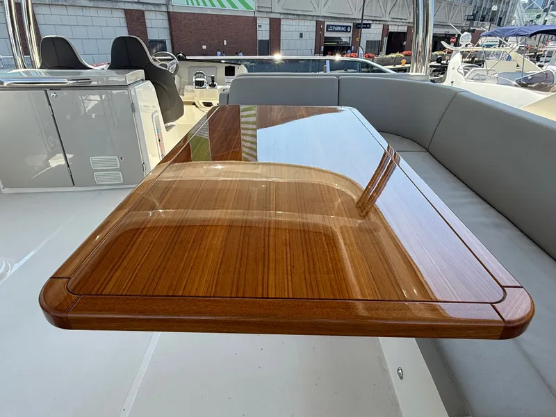 Slide: The Image of A sleek wooden table on a modern yacht's deck, surrounded by gray cushioned seating. - 13
